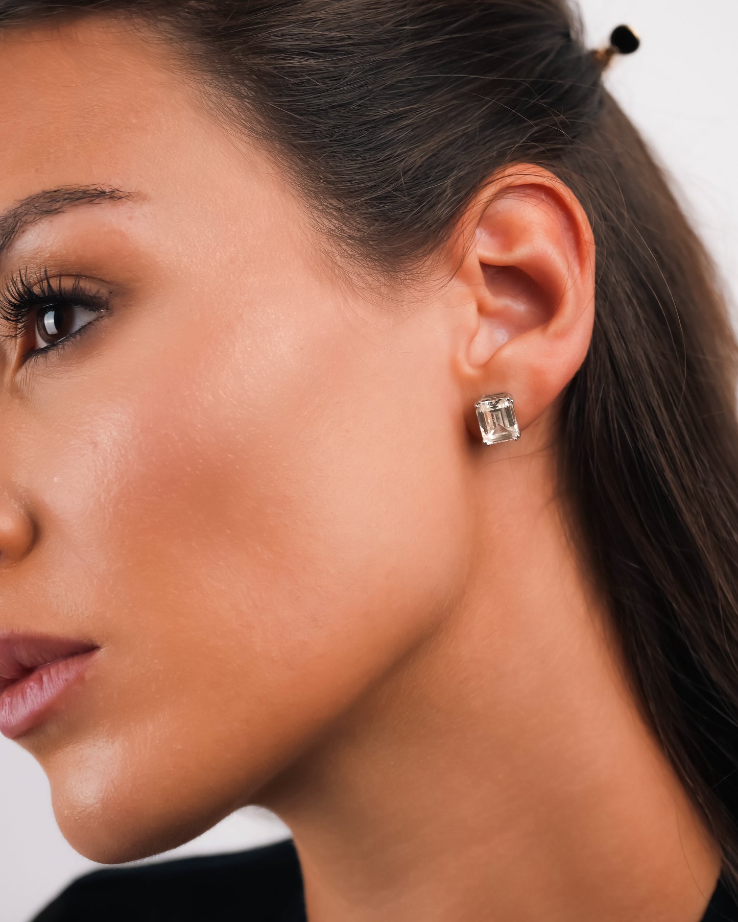 Close-up of a woman wearing a diamond earring with a neutral background